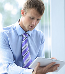 Handsome young man in a blue shirt using a tablet
