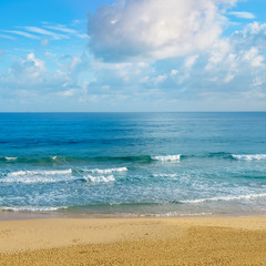 Deserted sandy beach of the Indian Ocean. In the blue sky cumulus clouds.