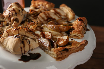 Tasty pear tart with chocolate sauce on cake stand, closeup
