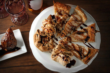 Tasty pear tart with chocolate sauce on cake stand, top view