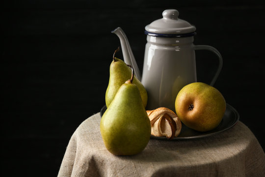 Still life with pears on table against dark background