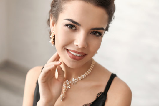 Beautiful young woman with elegant jewelry indoors
