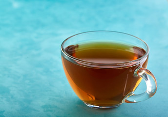 Glass cup of tea and chocolate cookies close-up on blue background.