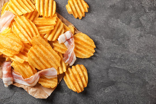 Crispy potato chips with bacon on table, top view