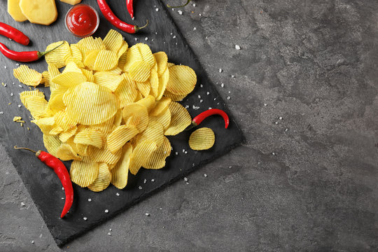Crispy potato chips with chili pepper and sauce on slate plate, top view