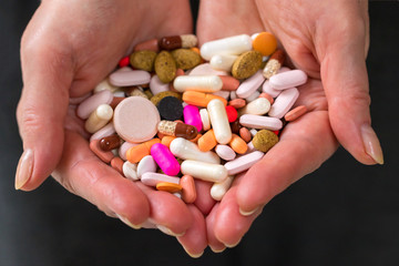 Female hands holding full of medicines,pills, vitamins or supplements.