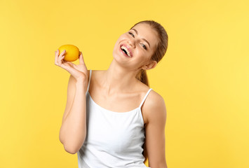 Beautiful young woman with ripe lemon on color background