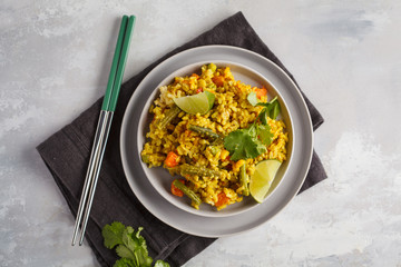 Vegetarian curry rice with vegetables in a gray plate. Top view, copy space. Healthy vegan food concept, detox, vegetable diet.