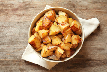 Bowl with tasty potato wedges on table