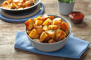 Bowl with tasty potato wedges on table
