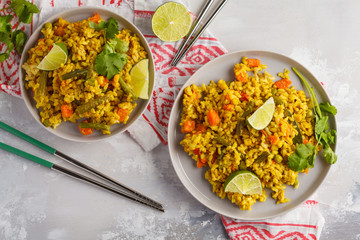 Vegetarian curry rice with vegetables and coconut cream in gray plates. Top view, copy space, food background. Healthy vegan food concept, detox, vegetable diet.