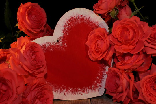 красивая розовая роза и фигурка сердца на черном фоне на деревянных досках        