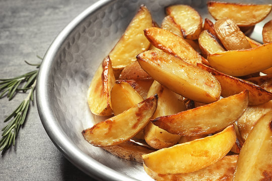 Dish with delicious baked potato wedges, closeup