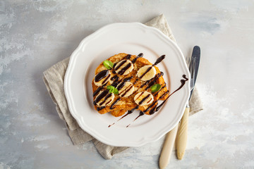 French toast with chocolate syrup and banana. Gray background, copy space, top view.