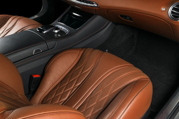 Modern Luxury car inside. Interior of prestige modern car. Comfortable leather seats. Orange perforated leather cockpit. Steering wheel and dashboard. automatic gear stick. Car interior