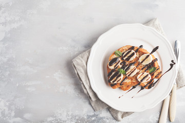French toast with chocolate syrup and banana. Gray background, copy space, top view.