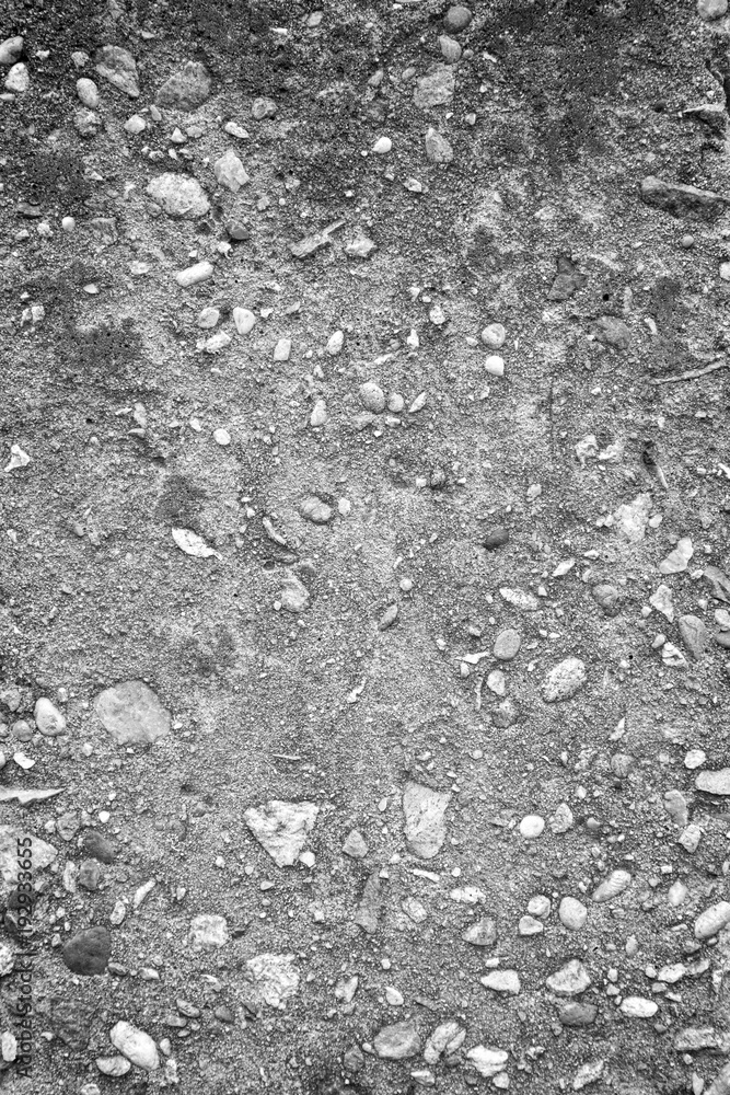Poster close-up of a concrete wall with small embedded pebbles texture background in black and white with v