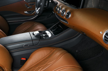 Modern Luxury car inside. Interior of prestige modern car. Comfortable leather seats. Orange perforated leather cockpit. Steering wheel and dashboard. automatic gear stick shift. Car interior