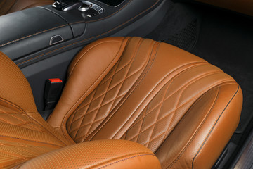 Modern Luxury car inside. Interior of prestige modern car. Comfortable leather brown seats. Orange perforated leather cockpit. Automatic transmission. Modern car interior details