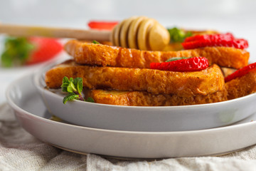 French toast with honey and strawberries in gray plate. Gray background