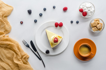 top view of piece of cake with berries and coffee on white table