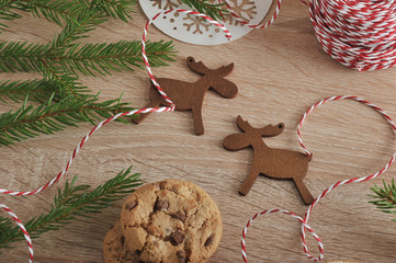 Christmas composition of oatmeal cookies, Christmas toys in the form of wooden figures of deer, braid and fir branches. Light wooden background. View from above. Close-up. Macro photography.