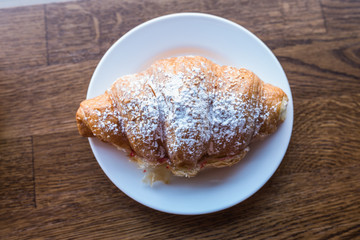 Croissant sandwich sprinkled with powdered sugar. Fast snack food