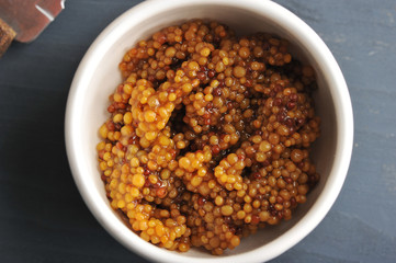 Granulated mustard in a cup. Seasoning from whole mustard seeds. View from above. Close-up. Macro photography.