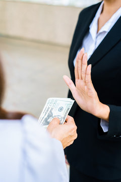 Businesswoman refusing money offered by a woman - anti bribery and corruption concepts.