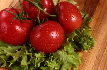 fresh tomatoes and lettuce leaves on oak table