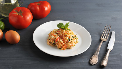 Traditional Turkish fried eggs with tomatoes (menemen). Nearby ingredients for cooking scrambled eggs: tomatoes, eggs, green peppers. In the frame of cutlery. Close-up.