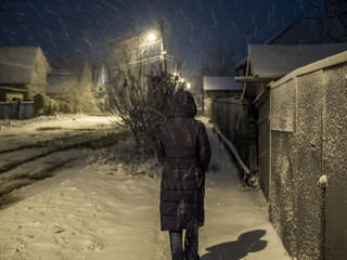 Woman walking along the street in winter evening