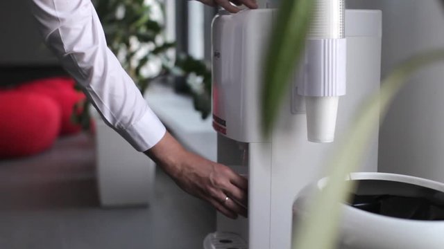 Close-up. Businessman Pouring Water From A Cooler In The Office