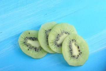 A few slices of kiwi on a blue wooden background. View from above. Close-up. Macro photography.