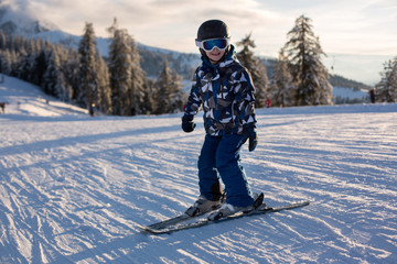 Fototapeta na wymiar Cute preschool child, boy, skiing on sunset in austrian Alps