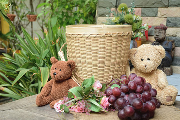 Teddy bear sitting on the table with grape and bamboo basket