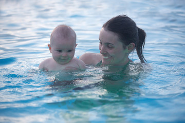 Little cute baby boy, swimming happily in a shallow pool