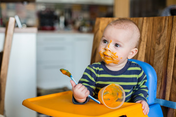 Little baby boy, eating mashed food for the first time