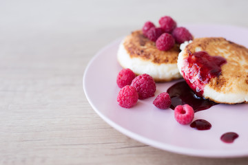 close-up of a curd that lies on a pink plate decorated with raspberries and jam with free space for text