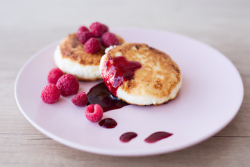 close-up of a cheese cake that lies on a pink plate with raspberry-flavored jam