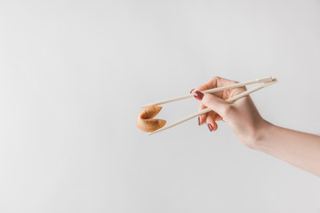 cropped image of woman holding chinese fortune cookie with chopsticks isolated on white