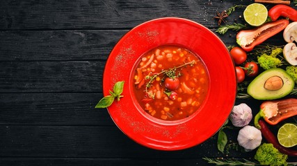 Tomato soup of corn, chicken and chili pepper. Top view. On a black wooden background. Copy space.