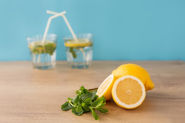 close-up two halves of a lemon and a whole near a sprig of mint on a wooden stench in the...