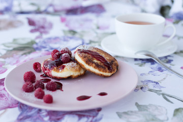 cheesecake on a pink plate with a cup of tea