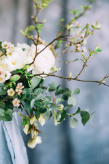 close-up of a twig with flowing leaves against a bouquet of white roses on a blue background