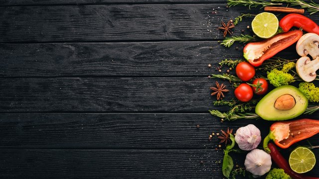 The background of cooking. A set of spices and fresh vegetables. Top view. Free space for your text. On a wooden background.