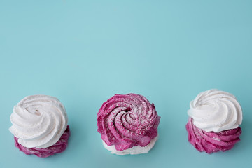 marshmallows of white and pink color are stacked on each other on a homogeneous mint background with a free space