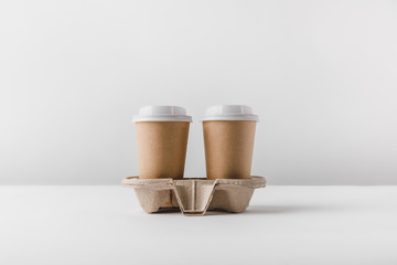 two coffee in paper cups in cardboard tray on tabletop