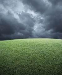 Green grass field with dark storm clouds before rain