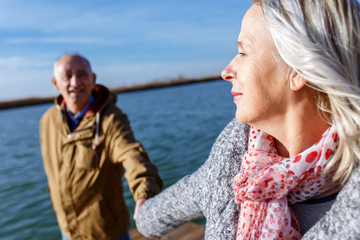 Portrait of happy senior couple by the lake on sunny autumn day.